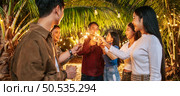 Portrait of Happy Asian group of friends having fun with sparklers outdoor - Young people having fun with fireworks at night time  - People, food, drink lifestyle, new year celebration concept. Стоковое фото, агентство Ingram Publishing / Фотобанк Лори