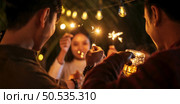 Portrait of Happy Asian group of friends having fun with sparklers outdoor - Young people having fun with fireworks at night time  - People, food, drink lifestyle, new year celebration concept. Стоковое фото, агентство Ingram Publishing / Фотобанк Лори