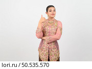 Portrait Young beautiful woman dress up in local culture in southern region showing gesturing finger thumb up looking to camera on white backgroup, copy space. Стоковое фото, агентство Ingram Publishing / Фотобанк Лори