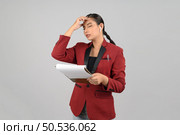 Portrait Asian young woman in officer uniform feel headache posture, use wireless earphone and reading report paper on clipboard in hand,  isolated on white background. Стоковое фото, агентство Ingram Publishing / Фотобанк Лори