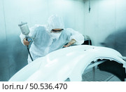 Auto mechanic in car spray room Inspecting the paint sprayed into the front bumper of the car that the pigment is complete, beautiful, harmonious with the original color of the car. Стоковое фото, агентство Ingram Publishing / Фотобанк Лори