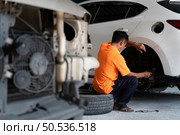 A auto mechanic checking the condition of a car’s brake discs and the condition of the tires that have been used for a while. Стоковое фото, агентство Ingram Publishing / Фотобанк Лори