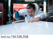 Auto mechanic use an electric polisher to polish the dried car paint. After passing the paint from the car painting room. Стоковое фото, агентство Ingram Publishing / Фотобанк Лори
