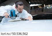 Auto mechanic use an electric polisher to polish the dried car paint. After passing the paint from the car painting room. Стоковое фото, агентство Ingram Publishing / Фотобанк Лори