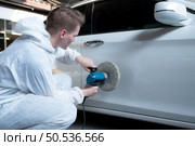 Auto mechanic use an electric polisher to polish the dried car paint. After passing the paint from the car painting room. Стоковое фото, агентство Ingram Publishing / Фотобанк Лори