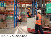 Managers, foremen and warehouse workers Consult together about getting the goods out of the warehouse to finish sending the small merchants tonight. Стоковое фото, агентство Ingram Publishing / Фотобанк Лори