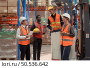 Managers, foremen and warehouse workers Consult together about getting the goods out of the warehouse to finish sending the small merchants tonight. Стоковое фото, агентство Ingram Publishing / Фотобанк Лори