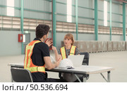 Meeting between designer and warehouse manager to organize the arrangement of product shelves in a huge, empty warehouse. Стоковое фото, агентство Ingram Publishing / Фотобанк Лори
