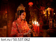 Chinese woman make wishes, pray, and light candles. On the occasion of the annual Chinese New Year festival, in a revered shrine or temple, And in Chinese where candles mean good luck and happiness. Стоковое фото, агентство Ingram Publishing / Фотобанк Лори