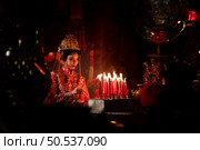 Chinese woman make wishes, pray, and light candles. On the occasion of the annual Chinese New Year festival, in a revered shrine or temple, And in Chinese where candles mean good luck and happiness. Стоковое фото, агентство Ingram Publishing / Фотобанк Лори