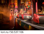 Male and female Chinese opera actors Light a candle to pray homage to the gods to enhance the prosperity for yourself on the occasion of the Chinese New Year festival. Стоковое фото, агентство Ingram Publishing / Фотобанк Лори
