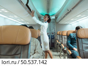 Flight attendant check the order of the passenger’s luggage storage. Стоковое фото, агентство Ingram Publishing / Фотобанк Лори