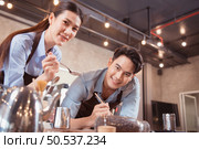 Before competing in the championship level coffee brewing competition, both of the baristas practice their coffee latte makeup techniques to become proficient. Стоковое фото, агентство Ingram Publishing / Фотобанк Лори