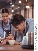 Before competing in the championship level coffee brewing competition, both of the baristas practice their coffee latte makeup techniques to become proficient. Стоковое фото, агентство Ingram Publishing / Фотобанк Лори