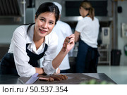 Portrait of student cooking apprentice Take notes on every step as the chef cooks in the culinary academy’s kitchen. Стоковое фото, агентство Ingram Publishing / Фотобанк Лори