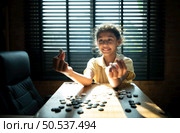 Portrait of a little girl in office room of house with a game of Go being learned to build concentration and intelligence. Стоковое фото, агентство Ingram Publishing / Фотобанк Лори