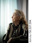 Lonely old woman Sit and look out the window where the morning sun shines in. Miss my loved ones who have been together for a long time, who have passed away without ever coming back. Стоковое фото, агентство Ingram Publishing / Фотобанк Лори