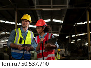 The foreign chief engineer came to inspect the old mechanical factory. There is an African female mechanic explaining details and progress reports on old machines being repaired to restore normal operation. Стоковое фото, агентство Ingram Publishing / Фотобанк Лори