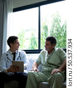 A young doctor who specializes in heart disease. Report and advise patients with symptoms of heart disease. that the results of the treatment improved until they were able to go home tomorrow. Стоковое фото, агентство Ingram Publishing / Фотобанк Лори