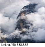 Mountain peak in low clouds at sunset in Nepal. Dramatic landscape with beautiful high rocks in fog, moody sky at dusk. Beautiful nature. Storm in Himalayan mountains. Scenery. Aerial view. Стоковое фото, агентство Ingram Publishing / Фотобанк Лори