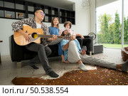 Multiethnic group of friends having fun playing guitar and singing together at home. Стоковое фото, агентство Ingram Publishing / Фотобанк Лори