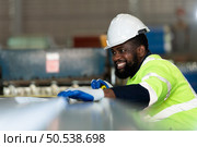 Young engineers engineers testing and confirming that the machinery at the factory that creates metal sheet tiles is functioning as intended. Стоковое фото, агентство Ingram Publishing / Фотобанк Лори