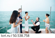 The appropriate time for a white man to propose to marry an Asian woman. on a yacht floating in the lovely water. Among friends who joined in congratulating. Стоковое фото, агентство Ingram Publishing / Фотобанк Лори