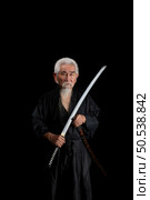 Senior Japanese samurai with katana sword on black background, studio shot. Стоковое фото, агентство Ingram Publishing / Фотобанк Лори