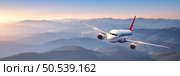 Plane is flying in colorful sky at sunset. Landscape with passenger airplane over mountains ranges and hills in fog, orange sky. Aircraft is landing. Business. Aerial view. Transport. Private Jet. Стоковое фото, агентство Ingram Publishing / Фотобанк Лори