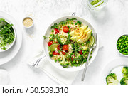 Couscous salad with broccoli, green peas, tomatoes, avocado and fresh arugula. Healthy natural plant based vegetarian food for lunch, israeli cuisine, top view. Стоковое фото, агентство Ingram Publishing / Фотобанк Лори