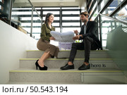 Both of businessperson sitting on stairs in office talk and exchange ideas on using natural energy in buildings before entering the meeting to present and consider. Стоковое фото, агентство Ingram Publishing / Фотобанк Лори