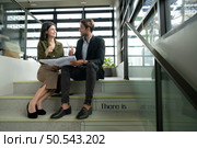 Both of businessperson sitting on stairs in office talk and exchange ideas on using natural energy in buildings before entering the meeting to present and consider. Стоковое фото, агентство Ingram Publishing / Фотобанк Лори