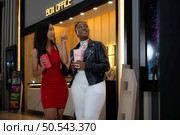Both of young woman stand and watch the movie program to watch today. Стоковое фото, агентство Ingram Publishing / Фотобанк Лори