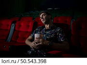 Man falls asleep while watching movie in cinema and popcorn in hand, Movie lacking interesting and boring. Стоковое фото, агентство Ingram Publishing / Фотобанк Лори