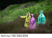 Group of friends in raincoats with backpacks on a hike in the forest, Prepare to hiking after the rain has stopped. Стоковое фото, агентство Ingram Publishing / Фотобанк Лори