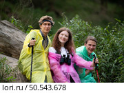 Group of friends in raincoats with backpacks on a hike in the forest, Prepare to hiking after the rain has stopped. Стоковое фото, агентство Ingram Publishing / Фотобанк Лори