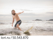 Young man surfing on the beach having fun and balancing on the surfboard. Стоковое фото, агентство Ingram Publishing / Фотобанк Лори