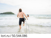 Young man surfing on the beach having fun and balancing on the surfboard. Стоковое фото, агентство Ingram Publishing / Фотобанк Лори