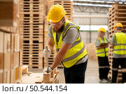 Young workers working in a woodworking factory, Using a hammer to work assembling pallet parts. Стоковое фото, агентство Ingram Publishing / Фотобанк Лори