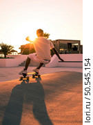 Surf skater training surfing moves near the beach at sunset. Стоковое фото, агентство Ingram Publishing / Фотобанк Лори