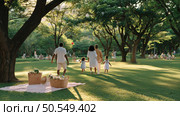 Family enjoys a sunny day in a lush green park while children play and adults gather for a relaxing outing. Стоковое AI-изображение, AI-художник Сергей Толмачёв / Фотобанк Лори