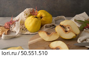 Ripe yellow quinces or queen apple fruits and sliced quince halves with seeds in craft cork plates on black rustic background. Стоковое фото, агентство Ingram Publishing / Фотобанк Лори