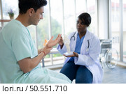 Doctor showing model of finger bones to patient in hospital. Medical and healthcare concept. Стоковое фото, агентство Ingram Publishing / Фотобанк Лори