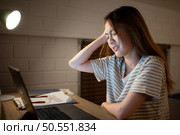 A young woman works on her laptop at home. It is characterized with headaches that occur when stressed. Стоковое фото, агентство Ingram Publishing / Фотобанк Лори