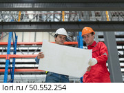 Portrait of two engineer discussing blueprints of electric train machinery Before undergoing regular inspection after being used for transporting passengers for a period of time. Стоковое фото, агентство Ingram Publishing / Фотобанк Лори