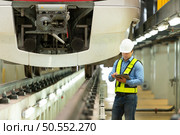 After the electric train is parked in the electric train’s repair shop, the electric train engineer inspects the electric train engine at the front of the procession. Стоковое фото, агентство Ingram Publishing / Фотобанк Лори