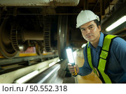 Engineers for electric trains After detecting difficulties with the electric train’s machinery use searchlights to locate and check damaged sections. In the electric train repair shop. Стоковое фото, агентство Ingram Publishing / Фотобанк Лори