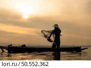 Silhouette of fisherman at sunrise, Standing aboard a rowing boat and casting a net to catch fish for food. Стоковое фото, агентство Ingram Publishing / Фотобанк Лори