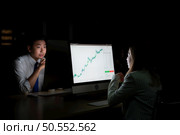 Both of young Asian broker international stock traders working together on desktop at night office, International financial investment company concept. Стоковое фото, агентство Ingram Publishing / Фотобанк Лори