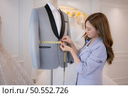 Asian fashion designers make sure the groom’s outfit is absolutely accurate and ready for the bride and groom to try on. Стоковое фото, агентство Ingram Publishing / Фотобанк Лори